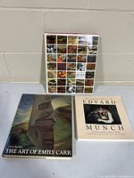 Three art books displayed together, showing front covers including Group of Seven book with small artwork images, Emily Carr book with totem pole, and Edvard Munch book.