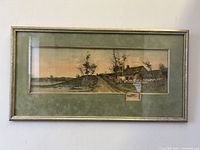 Full view of vintage framed rural landscape etching on wall showing frame and mat
