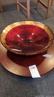 View of red and gold glass bowl on top of round wooden Lazy-Susan tray