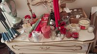 Overview of candles and candle accessories on tabletop including tapers, votives, candle holders, and candelabra