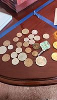 Coins spread on a table showing various sizes and colors including larger half dollar keychain and smaller coins