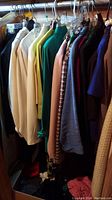 Photo of hanging assorted women's clothing including jackets, sweaters, skirts, and pants in muted color palette.