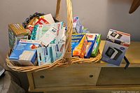 Photo of a basket filled with assorted healthcare products including bandages, toothbrushes, alcohol prep pads, and other medical supplies organized inside a woven basket.