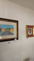 Framed Irish village scene and child portrait paintings hanging on wall