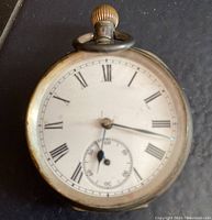 Front view of the antique pocket watch showing white dial with Roman numerals and seconds subdial