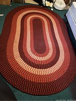 Top-down view of full oval braided rug on green carpet