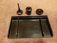 Photo of full ebony wood office supply set: tray, tall slender item, cylindrical holder, and small dish on carpet.