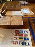 Photo shows a cardboard box open with multiple white envelopes inside. Below the box, a white envelope features a sheet of Canadian provincial flag stamps marked with circular 'Day of Issue' postmarks from Ottawa, dated 15.VI.79 (June 15, 1979).