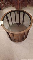 Full view of the round side table showing the tinted glass top and wood slatted sides.