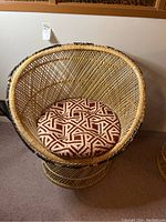 Front view of a woven rattan and wicker chair featuring a removable seat cushion with geometric pattern.