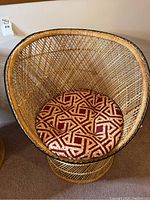 Top view of the rattan wicker chair showing the red and gold geometric patterned round seat cushion.