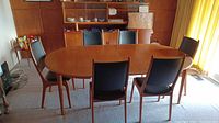 Full view of oval teak dining table extended with six chairs