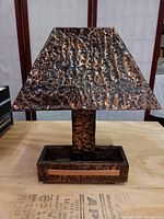 Front view of the Art Deco lamp showing the hammered copper tone metal base and matching shade on a wooden surface.