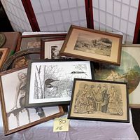 Various framed art prints laid on a table including Marilyn Monroe photo, fashion illustrations, and wildlife prints.