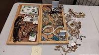 Full view of the collection of various costume jewelry pieces spread across two wooden trays.