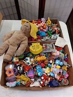 Photo showing a large box filled with many small collectible toys and a plush Paddington bear.