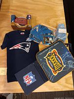 Full lot overview showing Patriots T-shirt, football cards, mini football, and stadium seat cushion.