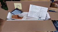 Photo of the boxed model boat showing wooden hull, brass fittings, instruction sheet, and parts in protective packaging.