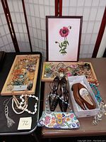 View of the entire lot including the framed red flower painting, costume jewelry trays, and two pairs of women's size 5 leather shoes