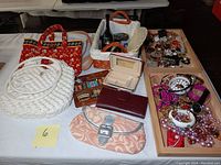 Full lot overview showing handbags, wallets, sewing kit, vase, fans, and costume jewelry trays