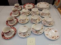 Top view of the full lot showing all tea set pieces including teacups, saucers, luncheon plates with floral design, and holiday-themed plates and cups from Charleton Hall Holiday.