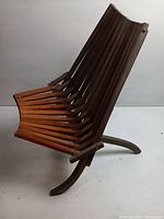 Side view showing the wooden slat construction forming the seat and backrest with curved legs for support.