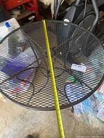 Round metal mesh patio table with tape measure showing diameter about 35.5 inches.