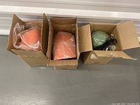 Top view of three dome-shaped lights in original cardboard boxes. Two orange lights on left, one green light on right.