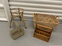 Photo showing rattan planter stand, rectangular woven basket with handles, wooden organizer basket, and decorative metal mesh basket arranged on floor