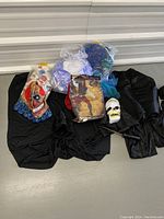 Photo of various costumes and masks laid out on black fabric with a plastic skull mask and colorful fabric pieces