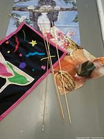 Three decorative flags laid flat with three wooden sticks beside them.