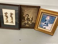 Three framed pictures side by side showing two figures made from butterfly wings, a child portrait with dog, and a girl painting.
