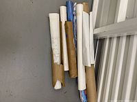 Image of multiple rolled posters and maps, in various tubes and paper wrapping