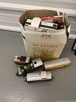 Box with toy train engine and three cars displayed outside with contents partially visible.