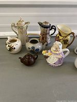 Photo of the full group of vintage teapots and ceramic pitchers showing variety in shapes and designs.