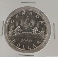 Reverse side of 1962 Canadian silver dollar featuring voyageur and Indigenous person in canoe with northern landscape.