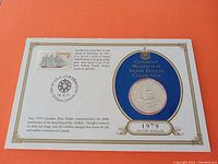 Front side of the silver dollar coin embedded in a collector card featuring a commemorative Canadian stamp with postal cancellation.