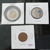 Three Canadian coins displayed separately in white holders. Top left is the 2021 Discovery of Insulin Toonie with blue colored motif. Top right is the 2011 Orca Whale quarter with blue coloring. Bottom is the 1971 Canadian penny with some wear, labeled 1971 on holder.