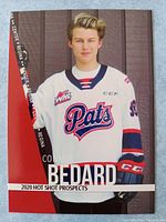 Front side of the card showing Connor Bedard in Regina Pats jersey with white background and red diagonal stripe.