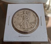 Obverse side of the 1941 USA half dollar coin showing Walking Liberty design, coin in protective holder, details of date and 'In God We Trust' visible.