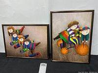 Photo of two framed colorful abstract art pieces, sized 12 x 16, featuring people on scooters and a tricycle