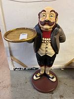 Front view of the waiter statue holding a golden tray on one side, standing on a round base, showing full body and colors.