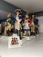 Front angled photo of Goebel porcelain figurines showing detailed historic military and civilian figures in colorful uniforms
