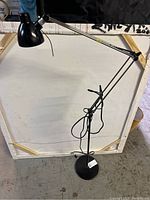 Full view of the black articulated floor lamp showing the adjustable arm and round base.