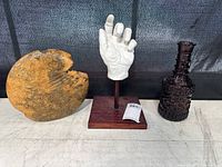 Full view of all three items, including the wooden vase, glass vase, and hand sculpture