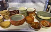 Wide view of Denby dishware grouping including plates, bowls of various sizes and colors arranged on a table