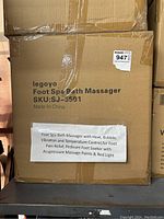Closed cardboard box labeled "Legoyo Foot Spa Bath Massager" with product description sticker listing features including heat, bubble, vibration, temperature control for foot pain relief and pedicure use.