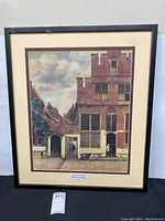 Full view of the framed art print showing the street scene with buildings and people.