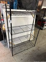 Front angle view of the black metal wire adjustable storage shelf showing four wire shelves and tubular poles.