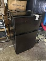 Full view of the black mini fridge with freezer section on top.